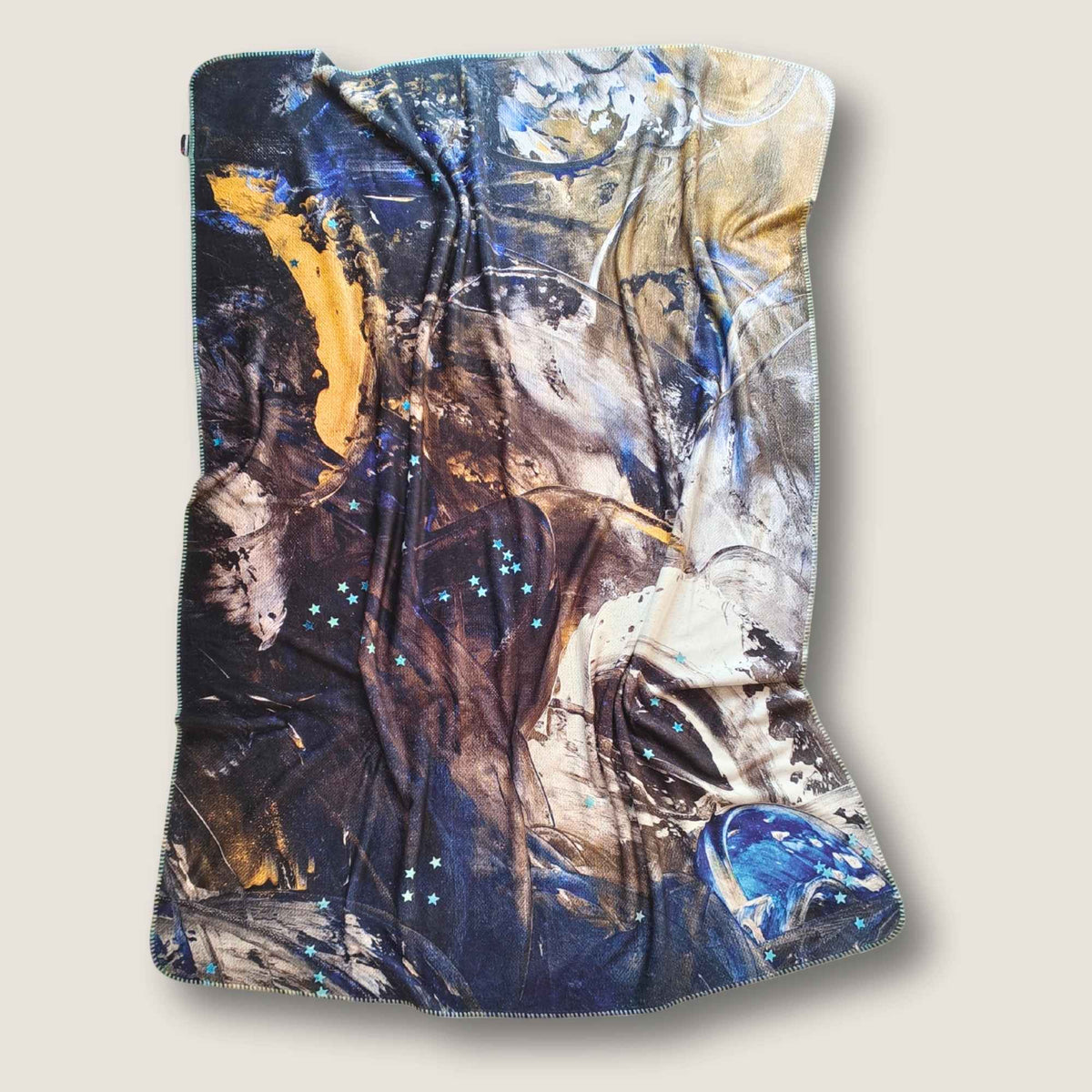 FEEL Kuscheldecke mit abstraktem Originalkunstmotiv von MYSTIQUE in Dunkelblau, Schwarz, Creme, Grau und Gold, freigestellt vor weißem Hintergrund - INTO THE WOO.