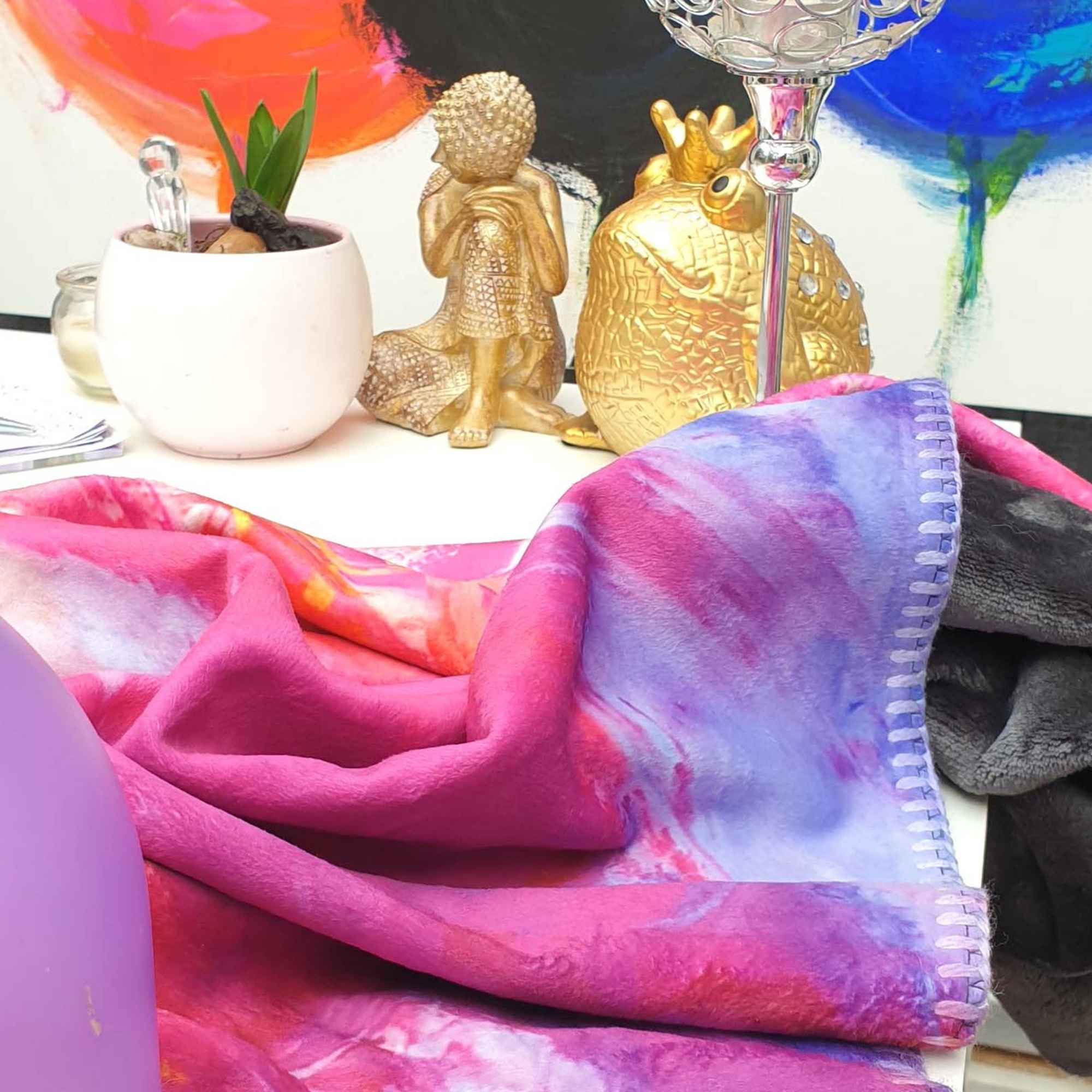 Kuscheldecke „LA MER“ auf einem Tisch vor goldenen Dekofiguren