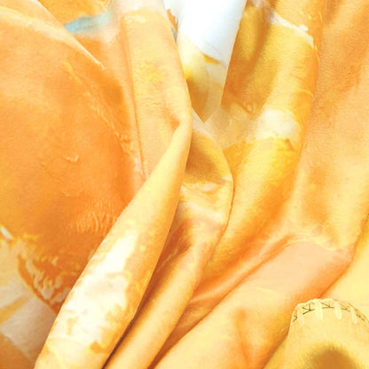Weiche, gold-orangefarbene Kuscheldecke in Nahaufnahme -fließender Stoff mit samtiger Struktur und warmen Farbtönen.